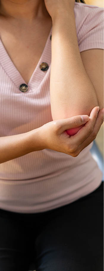 Close-up of a young woman holding her wrist with a red note of elbow pain  Looking at the concept of medical therapy