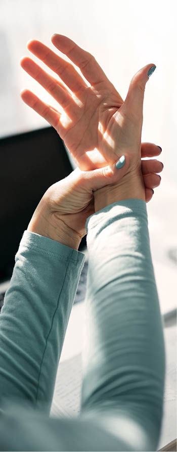 Woman with hand, joint, arm and finger pain, stretching and massaging during work on a laptop 