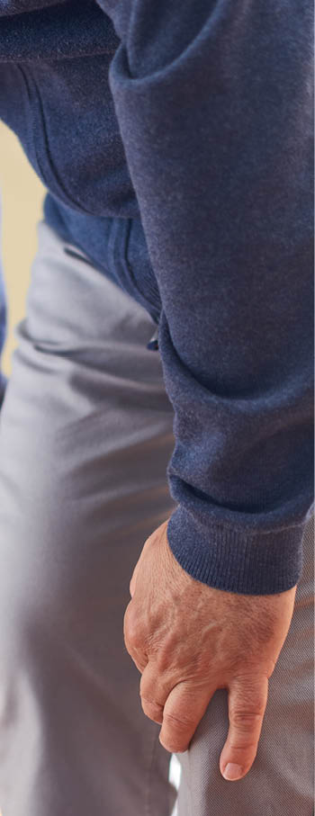 Vertical photo of a middle-aged Caucasian man getting up with difficulty from a chair in his sunny home 